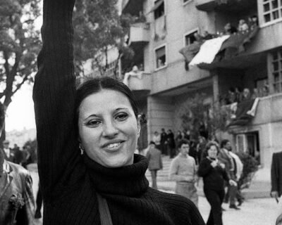 Giovane donna manifesta al corteo del 1° maggio, innalzando un garofano.